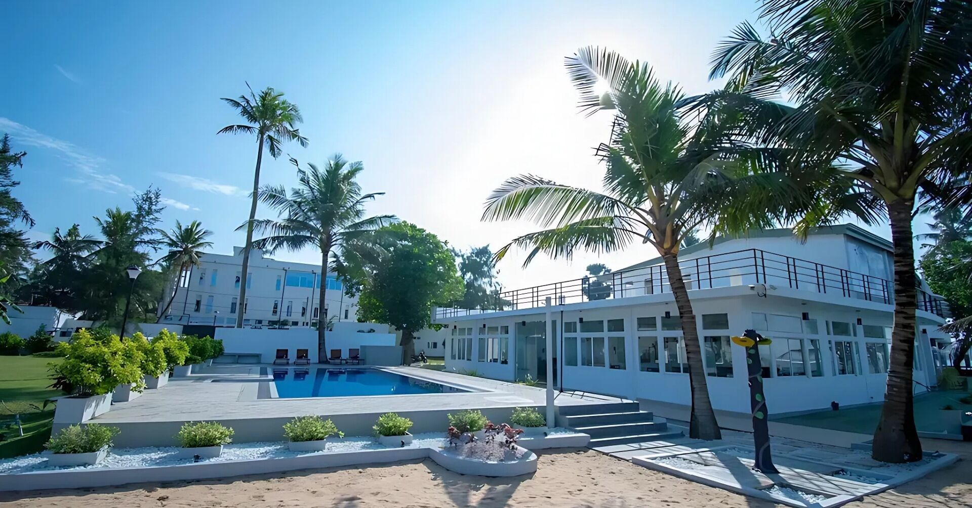Ein modernes Hotel mit Pool, Palmen und einem zweistöckigen Gebäude.