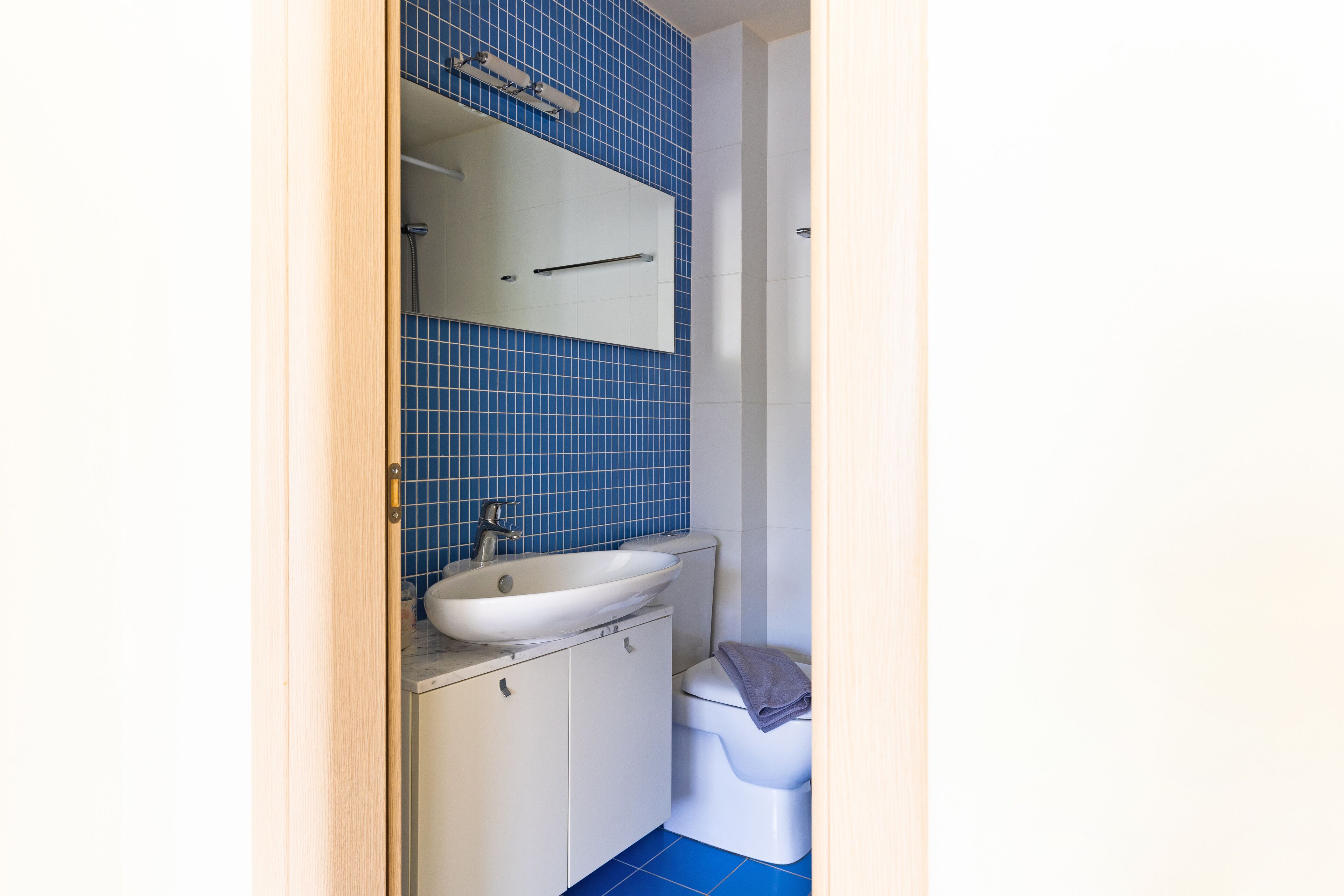 A bathroom with a white sink, a mirror, and a toilet.
