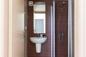 Une salle de bain avec un lavabo blanc, un miroir et une douche.