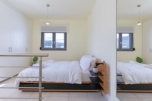 Une chambre à coucher moderne avec un lit, une table de chevet, un miroir et une fenêtre.