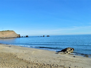 A beach with a rocky cliff, calm sea, and clear sky. - Cozy studio near the beach with private parking (Cap d'Agde)
