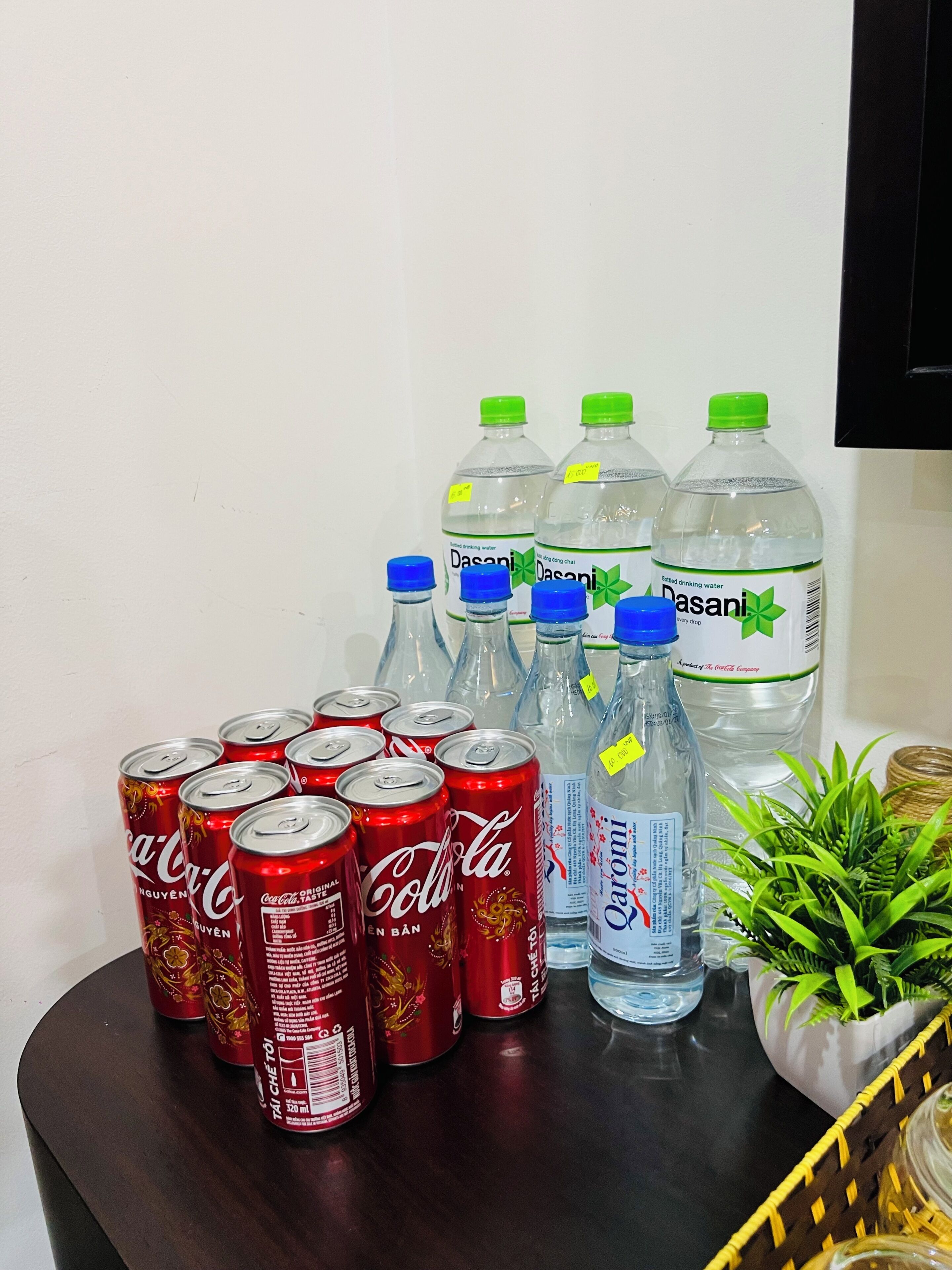 Pöydällä on erilaisia juomatölkkejä ja -pulloja, kuten Coca-Colaa ja Dasani-mineraalivettä.