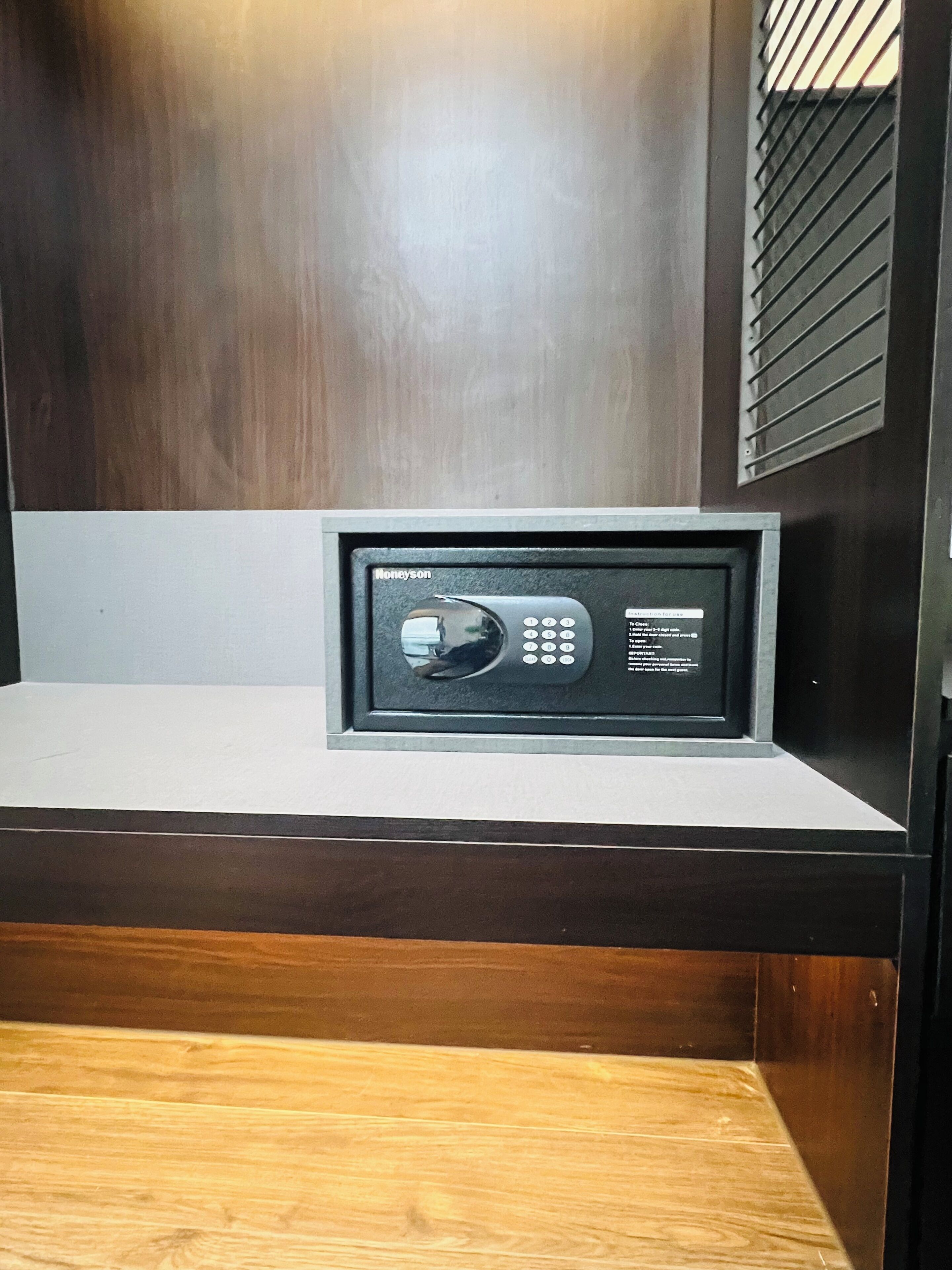 A safe deposit box with a keypad, a wooden floor, and a dark wall.