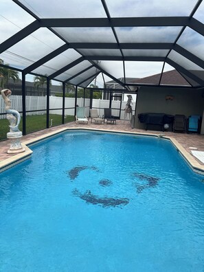 Relax by the pool, surrounded by a patio with lounge chairs and barbecue setup.
