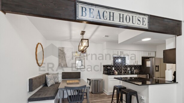 A modern kitchen with black and white cabinetry, a central island, and a hanging light fixture. - 2585 Forest Ridge 2 Bedroom Condo (Fernandina Beach)