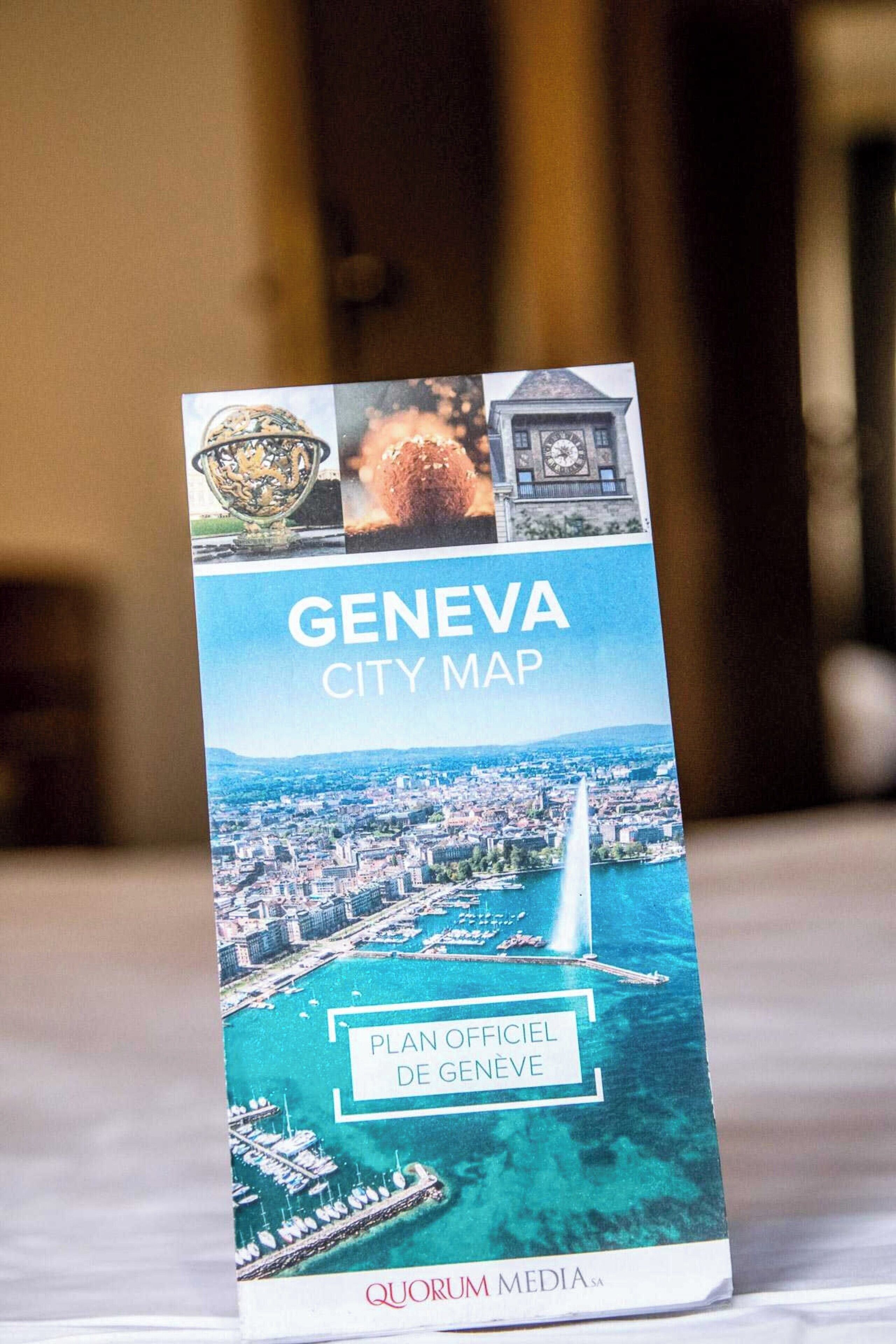 Folleto de un mapa de la ciudad de Ginebra que muestra un paisaje urbano, una torre de reloj y un puente.
