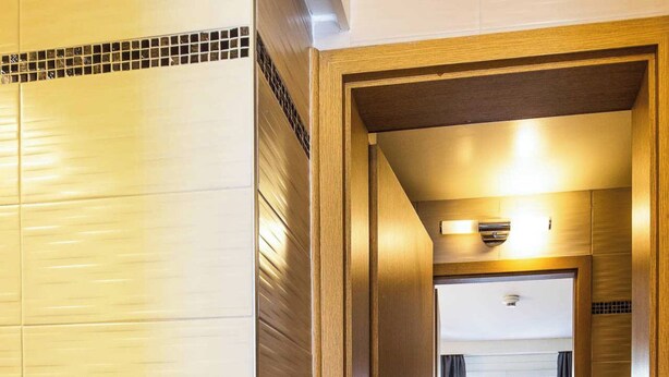 A hotel room with a wooden door, a small table, two beds, and a window with curtains. - Charming Apartment - 1br-4p- Geneva (Geneva)