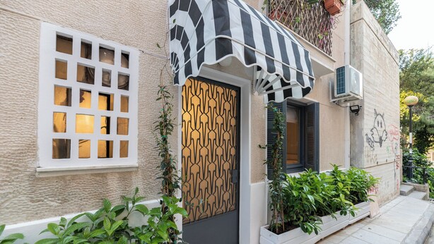A building with a distinctive black and white striped awning, a patterned door, and a small window with a grid design. - O&O Group - Kolonaki Urban Residence (Athens)