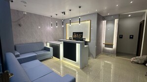 Ett modernt receptionsområde med en soffa, en receptionsdisk och en väggmonterad TV.