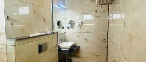 A modern bathroom with a glass shower enclosure, a white toilet, a sink with a mirror, and a towel rack.