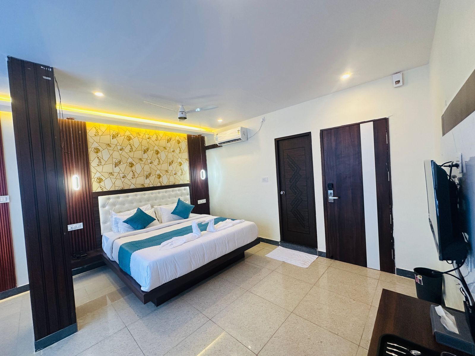 A hotel room with a large bed, a TV, and a wardrobe.