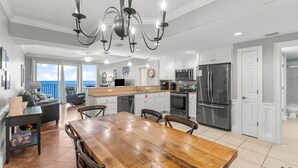 A spacious kitchen with a wooden dining table, white cabinets, and stainless steel appliances. - Treasure Island condo - pool, hot tub and gulf views (Panama City Beach)