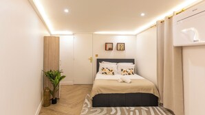 A modern bedroom with a bed, bedside tables, a potted plant, and a wall-mounted air conditioning unit. - Exceptional apartment with Jacuzzi & well-being in the heart of Paris Metro (Paris)