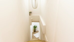A narrow staircase with a mirror at the top, a vase with flowers, and a potted plant at the bottom. - Exceptional apartment with Jacuzzi & well-being in the heart of Paris Metro (Paris)