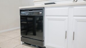 A kitchen with a black dishwasher and white cabinets.