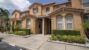 A row of two-story houses with a uniform architectural style, featuring arched windows and a consistent color scheme.