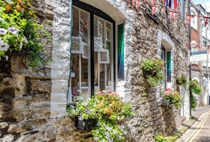 A stone building with a shop window displaying various items. - Kings Cross by Pureserviced (Plymouth)
