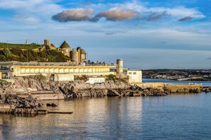A coastal town with a historic castle, a bridge, and a waterfront promenade. - Kings Cross by Pureserviced (Plymouth)
