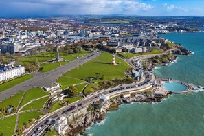 An aerial view of a coastal city with a prominent lighthouse, a large green park, and a marina. - Kings Cross by Pureserviced (Plymouth)