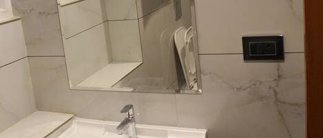 A bathroom with a white sink, a mirror, and a towel rack.