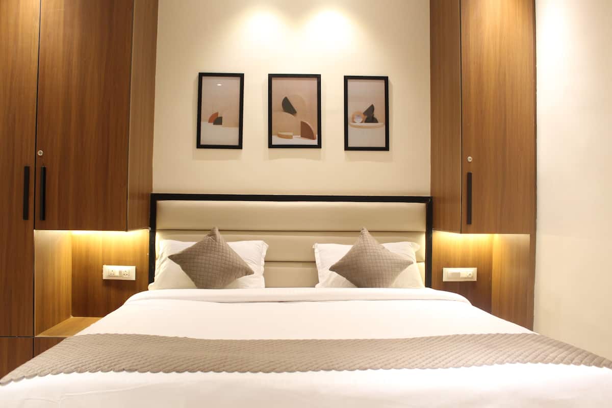 A neatly made bed with a headboard, two bedside tables, and three framed artworks on the wall.