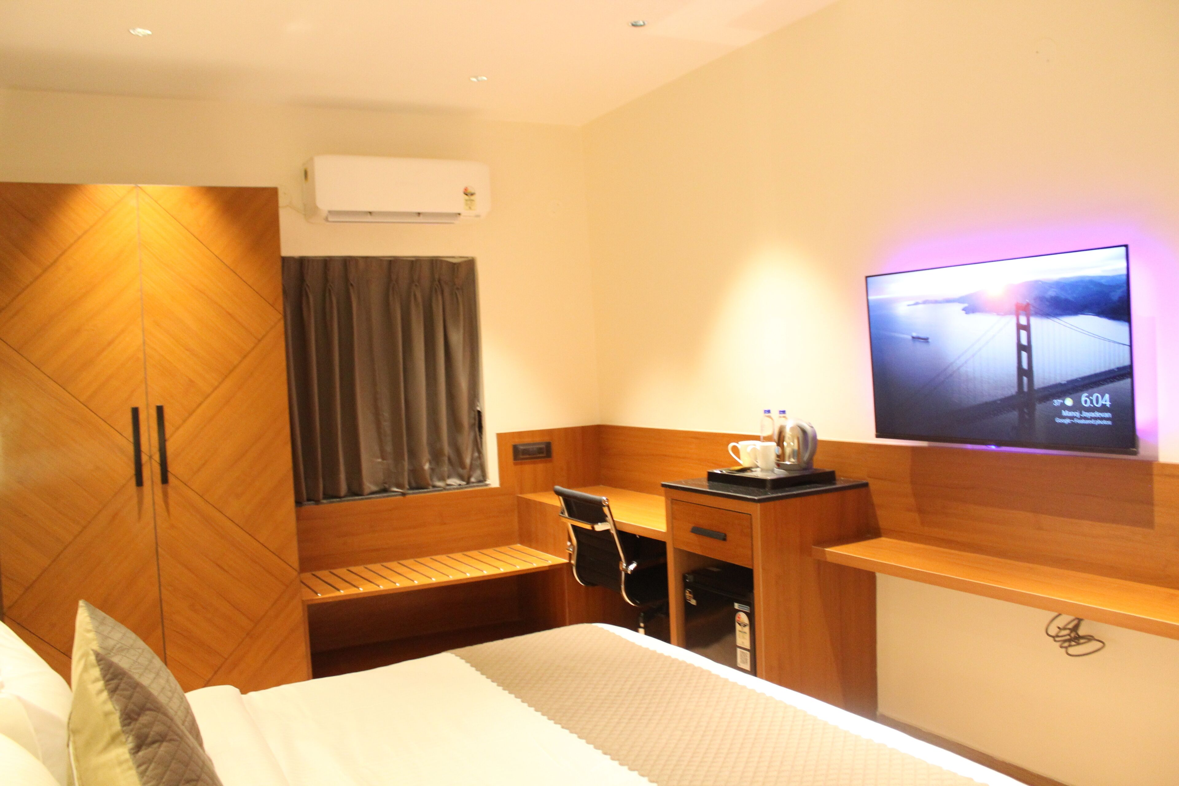 Een hotelkamer met een bed, een bureau, een stoel, een aan de muur bevestigde televisie en een kledingkast.