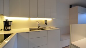 Eine moderne Küche mit weißen Schränken, einer Edelstahl-Spüle und einer Kaffeemaschine.