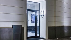 A hotel entrance with a glass door, a metal door frame, and a wall-mounted light fixture. - Il Papero a Napoli (Naples)
