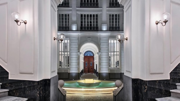 A grand entrance with a marble staircase, a central fountain, and a large arched doorway. - Il Papero a Napoli (Naples)