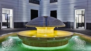 A modern indoor fountain with a central water feature surrounded by a circular pool, set against a building with a symmetrical facade and balconies. - Il Papero a Napoli (Naples)
