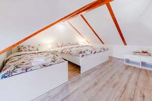 Une chambre avec deux lits, des poutres en bois, une commode blanche et une petite table avec un plateau.
