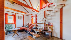 Una sala de estar moderna con una escalera de madera, un sofá, una mesa de centro y una pequeña mesa con juguetes.