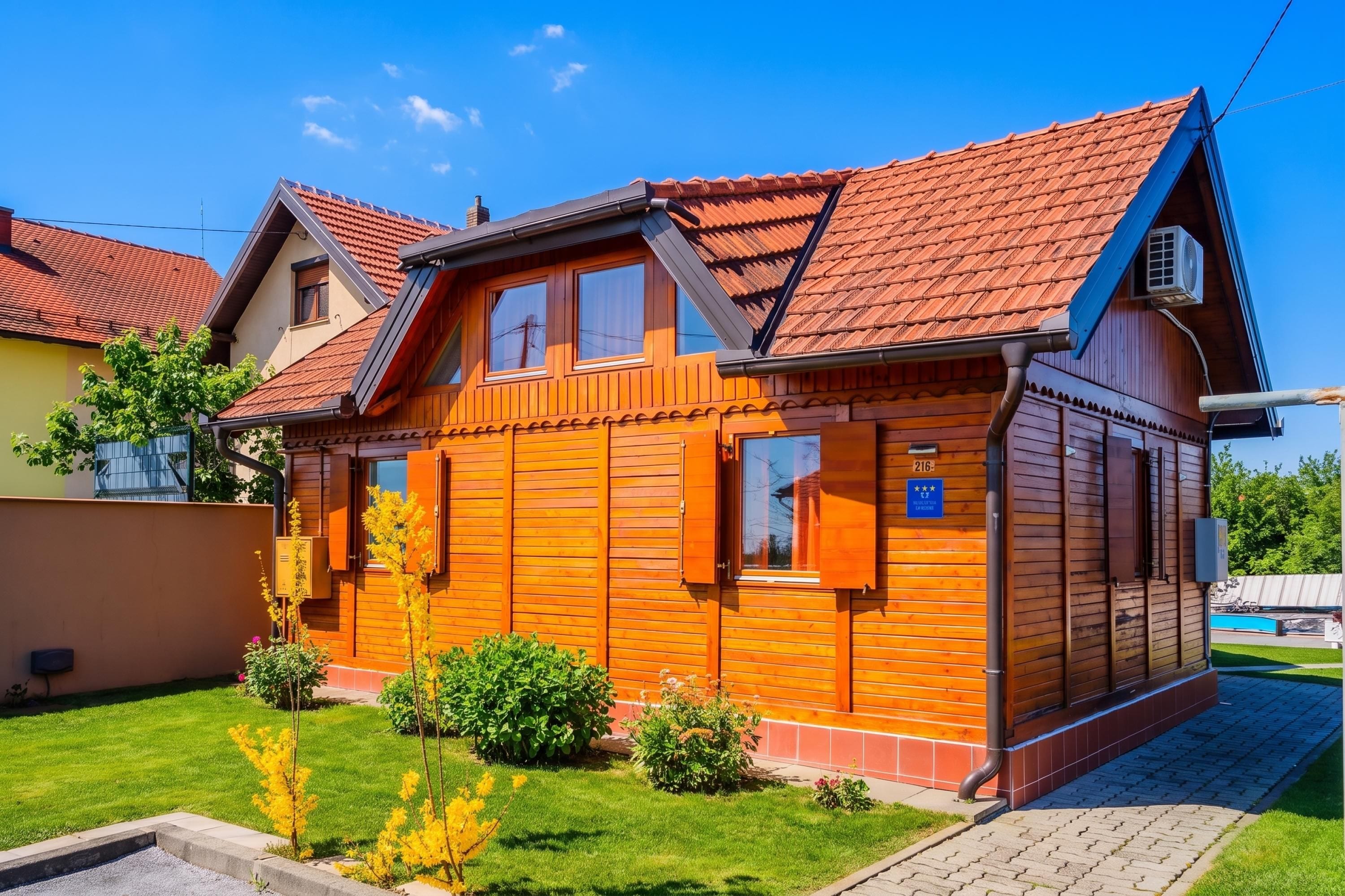 Une maison en bois avec un toit en pente, un petit porche à l’avant et une pelouse bien entretenue.