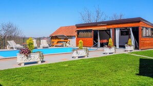 Una casa moderna con piscina, mobiliario exterior y césped cuidado.