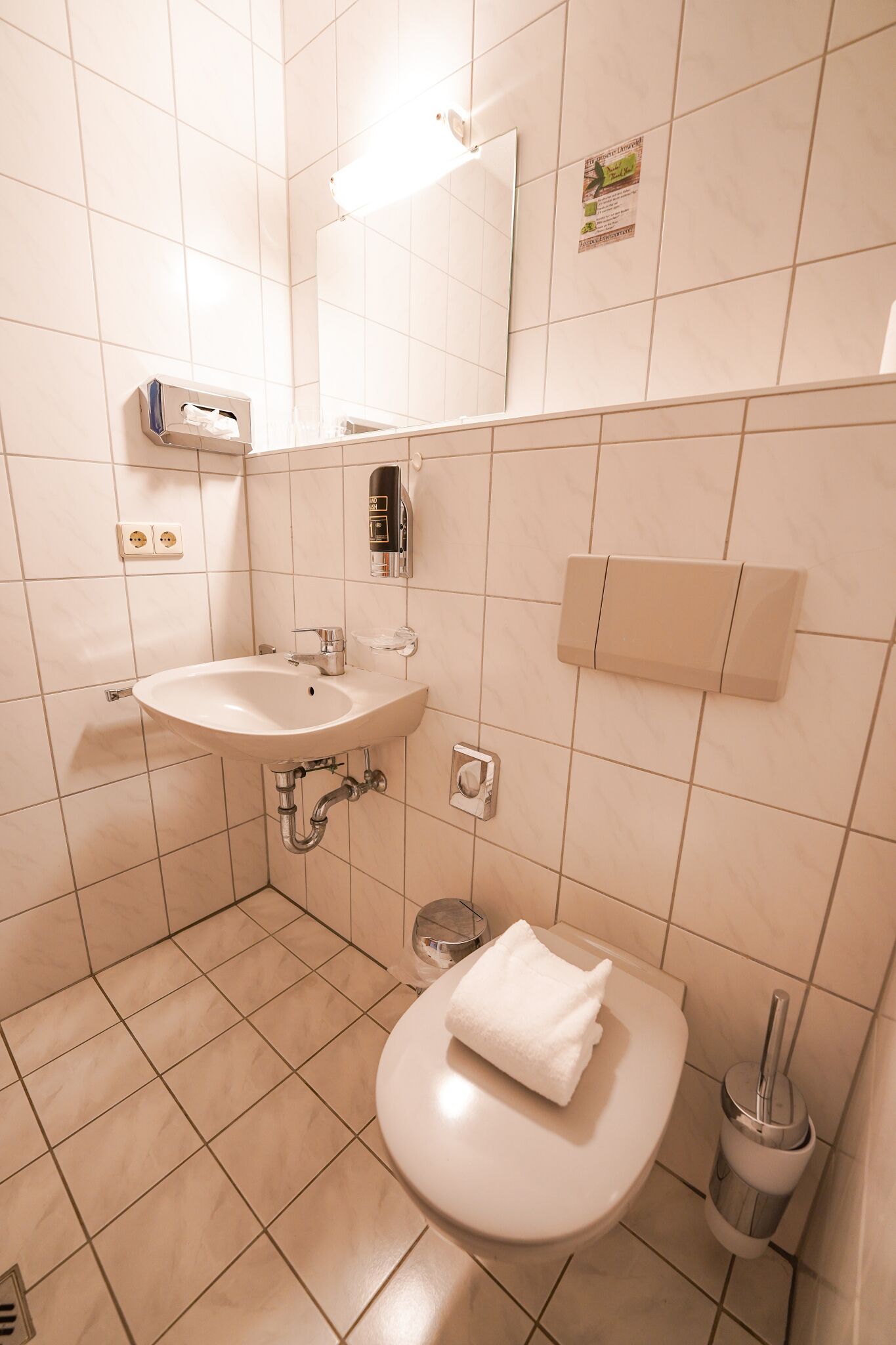 A bathroom with a sink, toilet, and hand dryer.