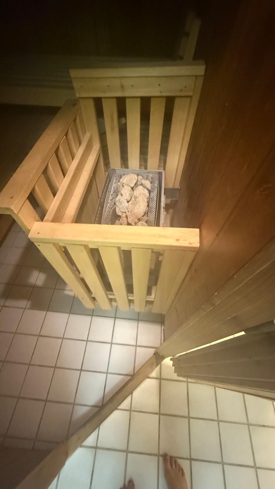 Un escalier en bois, surmonté d’une grille métallique, mène à un sol carrelé.
