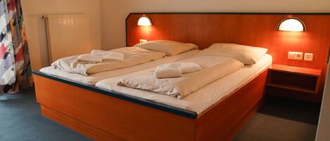 A double bed with a wooden headboard, two bedside tables with lamps, and a radiator.