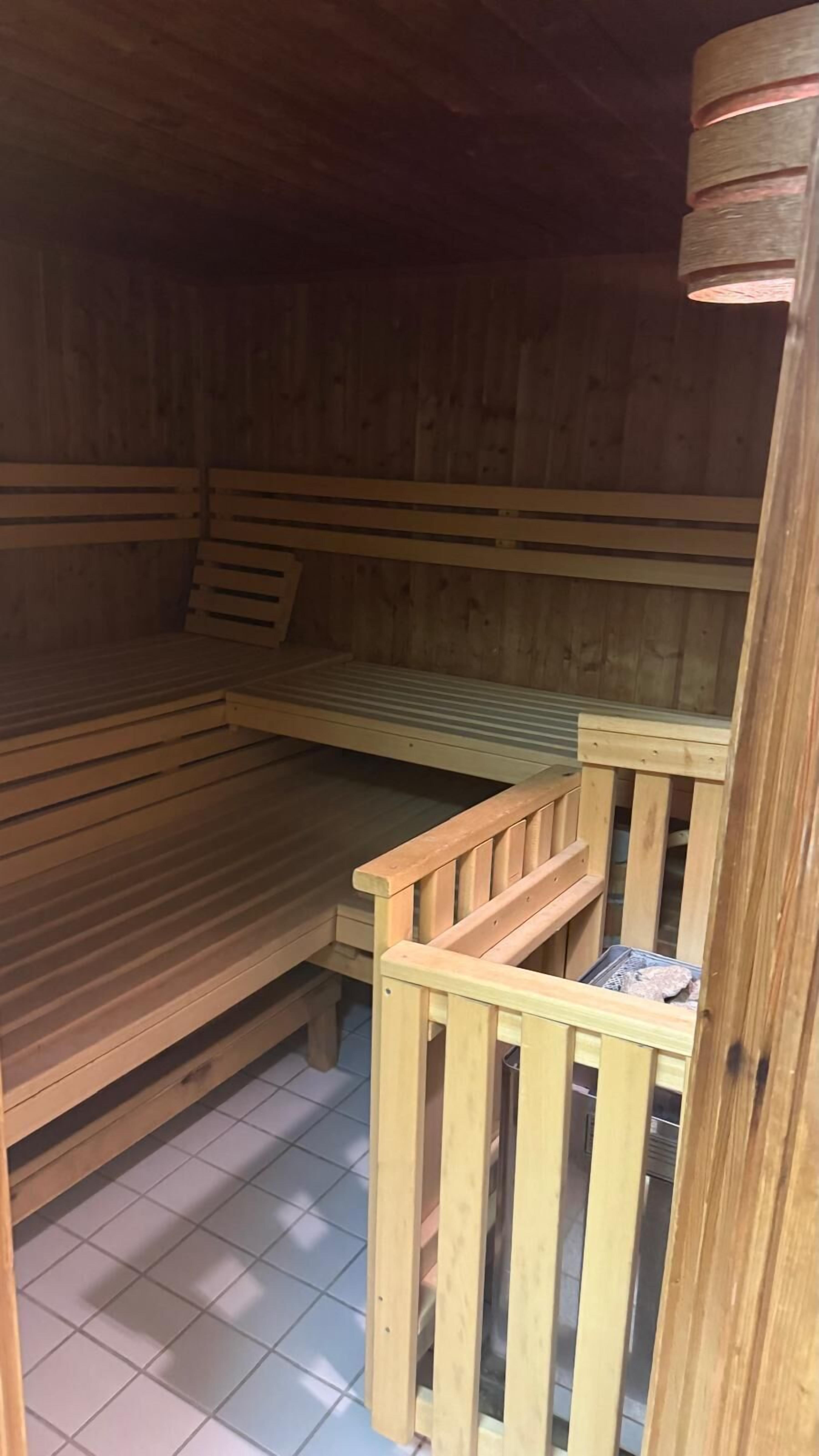 A wooden sauna with benches and a wooden railing.