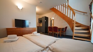 Een hotelkamer met twee bedden, een televisie, een houten trap en een kleine kitchenette.