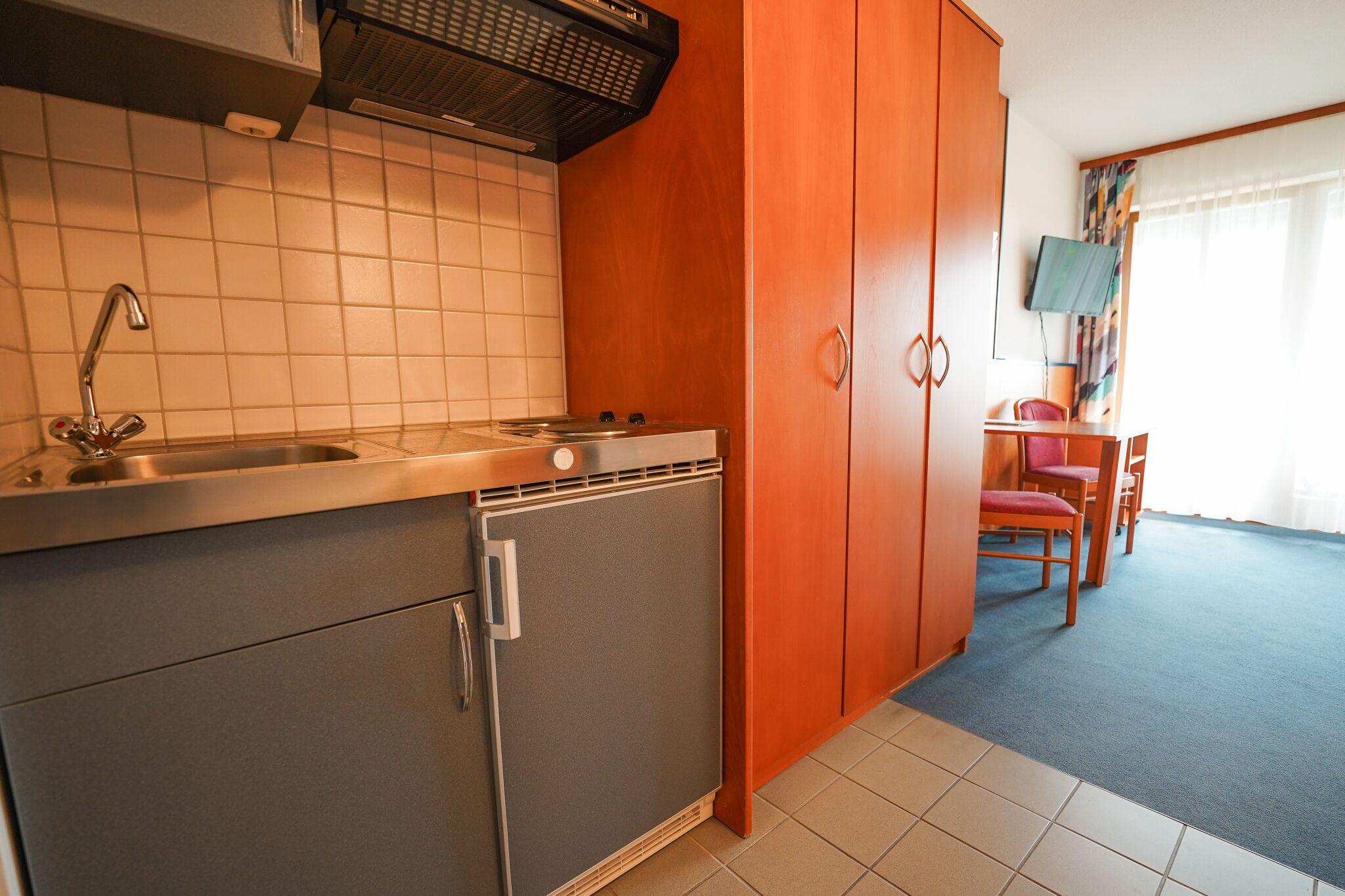 A compact kitchen with a sink, stove, and refrigerator. There is a dining area with a table and chairs.