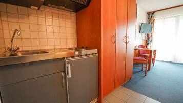 A compact kitchen with a sink, stove, and refrigerator. There is a dining area with a table and chairs.