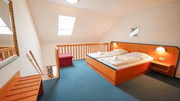A bedroom with a wooden bed, a red bench, a mirror, and a skylight.