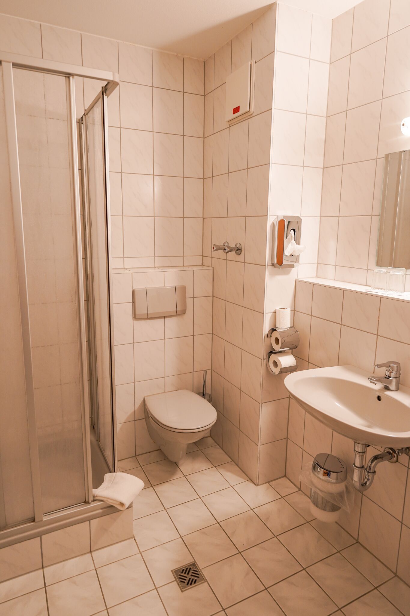 Baño con ducha, inodoro, lavamanos y secamanos.