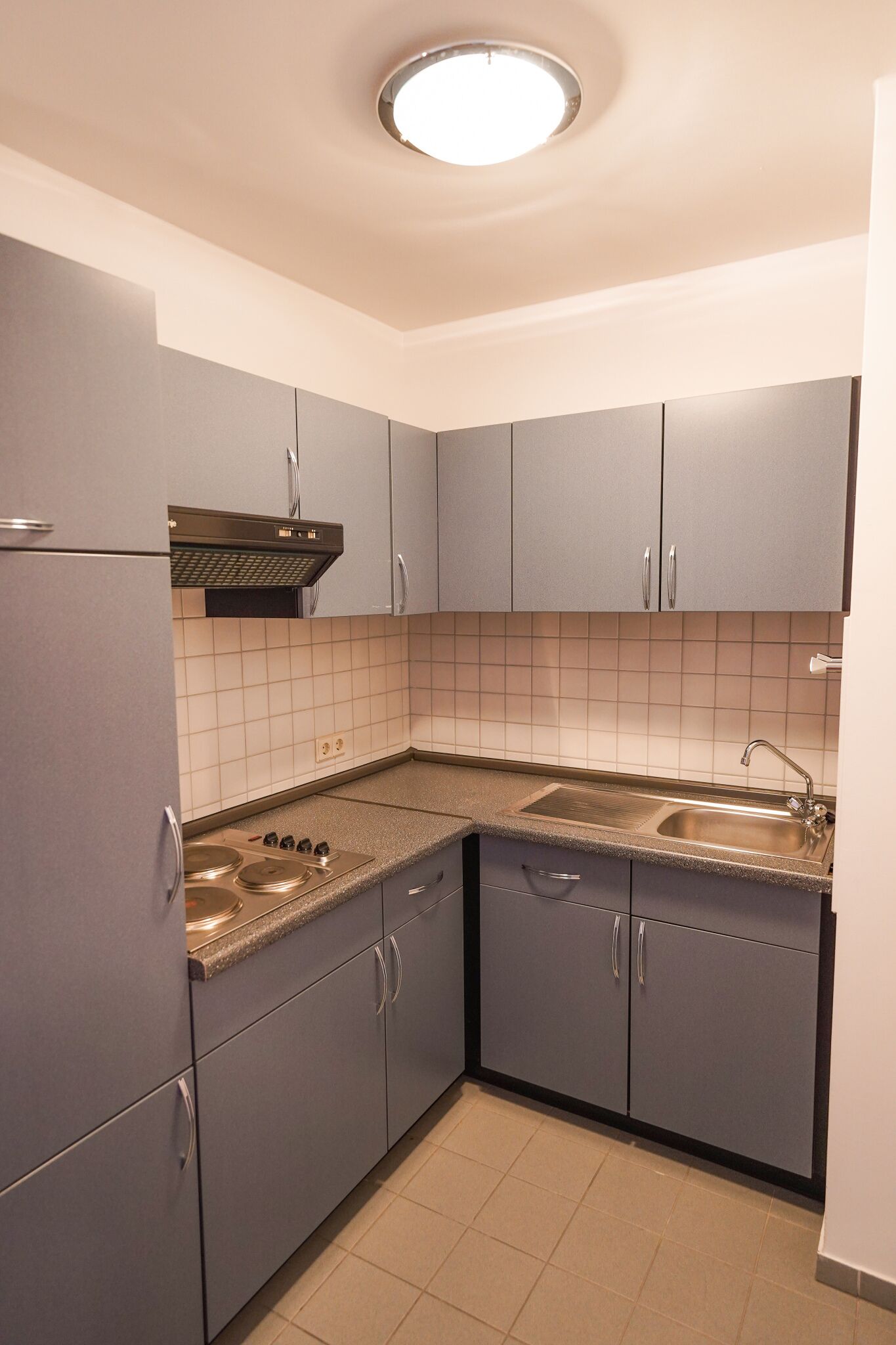A compact kitchen with grey cabinets, a built-in stove, and a sink.