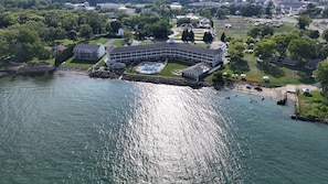 An aerial view of a waterfront property with a swimming pool, a dock, and a small pier.
