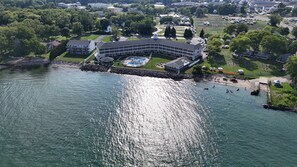 An aerial view of a waterfront property with a swimming pool, a dock, and a small pier.