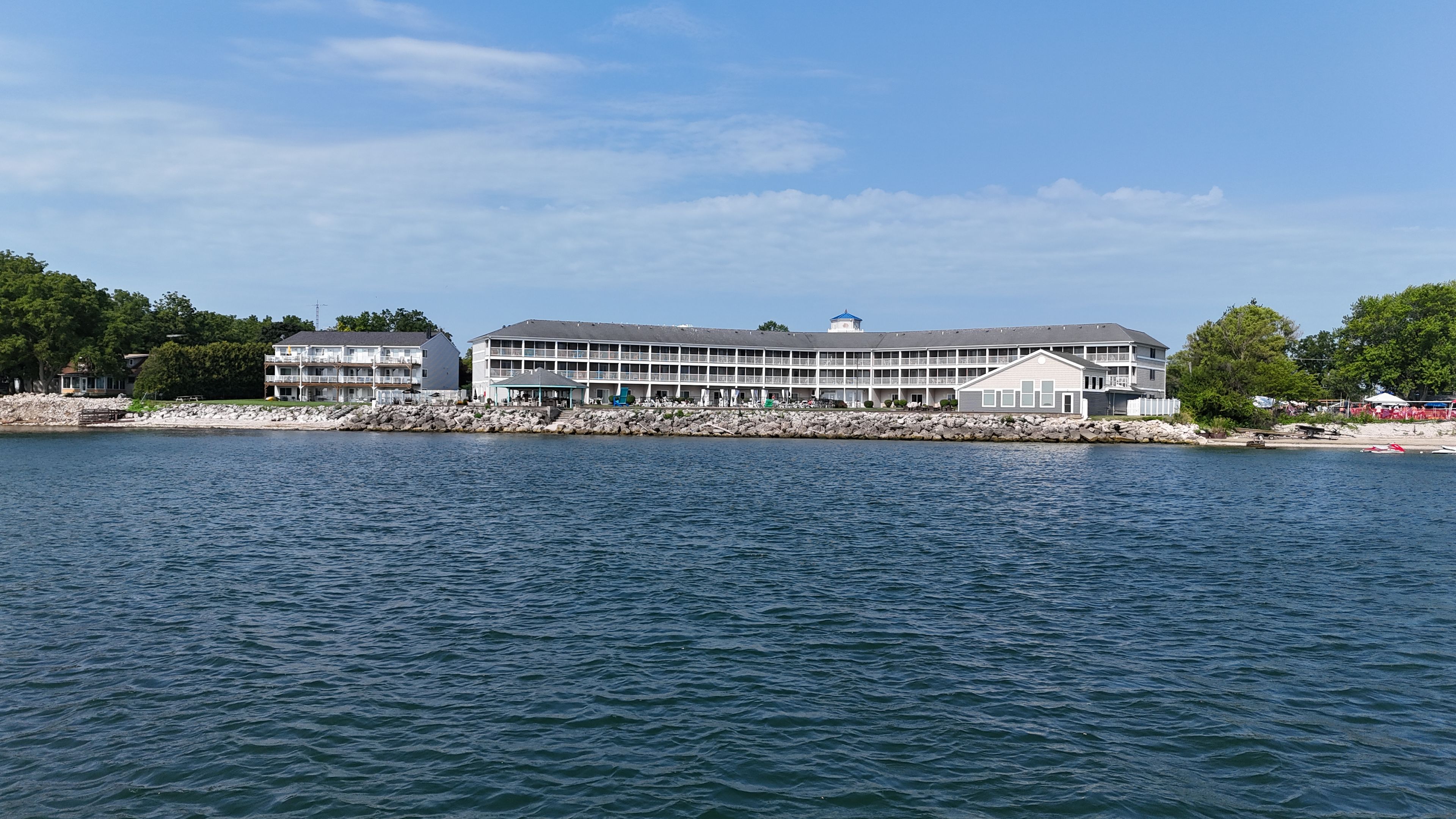 A waterfront hotel with multiple balconies, a covered outdoor area, and a view of the water.