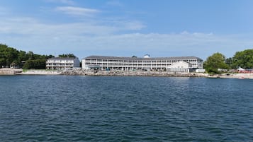 A waterfront hotel with multiple balconies, a covered outdoor area, and a view of the water.