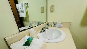 Une salle de bain d’hôtel équipée d’un lavabo, d’un miroir et d’articles de toilette.