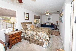 A bedroom with a bed, a dresser, a ceiling fan, and a window with blinds.